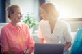 Female nurse and senior woman smiling while using laptop Royalty Free Stock Photo