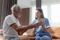 Female nurse takes care of senior patient and teaches him to use digital tablet at living room house, elderly mature grandfather Royalty Free Stock Photo