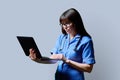 Female nurse using laptop, profile view on gray studio background Royalty Free Stock Photo