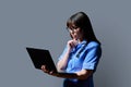 Female nurse using laptop, profile view on gray studio background Royalty Free Stock Photo