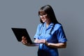 Female nurse using laptop, profile view on gray studio background Royalty Free Stock Photo