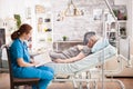 Female nursing sitting on chair next to old woman in nursing home Royalty Free Stock Photo