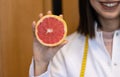 Female nutritionist in apron and tape measure holding grapefruit Royalty Free Stock Photo