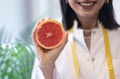 Female nutritionist in apron and tape measure holding grapefruit Royalty Free Stock Photo