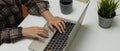 Female office worker typing on computer keyboard on office desk with laptop, supplies and decorations