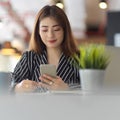 Female office worker using smartphone while sitting at worktable in office room Royalty Free Stock Photo