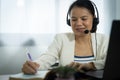 Female operator wearing a headset and writing in a notebook. She is smiling and she is happy Royalty Free Stock Photo