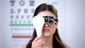Female in optical trial frame closing eye and squeezing, poor vision problems