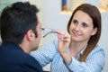 female optician fitting eyeglasses to male client