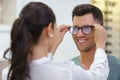 Female optician fitting male clients eyeglasses