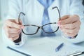 Female optician hands giving new glasses to customer for testing and trying close-up. Eye doctor with client comparing Royalty Free Stock Photo