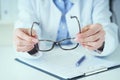 Female optician hands giving new glasses to customer for testing and trying close-up. Eye doctor with client comparing Royalty Free Stock Photo