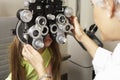 Female Optician In Surgery Giving Girl Eye Test