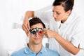 Female Optometrist Checking Patient`s Vision With Trial Frame