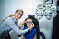 Female optometrist examining young patient with phoropter Royalty Free Stock Photo