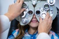 Female optometrist examining young patient on phoropter