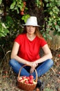 Female outdoors portrait. A happy middle-aged woman sits under a tree in an apple orchard near a full basket of apples. Royalty Free Stock Photo