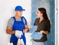 Female owner consults with a professional builder about installing a ceramic tile in remodeling bathroom