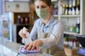 Female Owner Delicatessen Wearing Face Mask Cleaning Counter With Sanitising Spray
