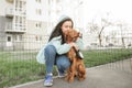 Female owner hugs a dog against the backdrop of a city fund. Girl loves her dog and hugs her for a walk. Photo of a gray dog and Royalty Free Stock Photo