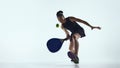 Female padel player reaching low ball with racket in studio. Royalty Free Stock Photo