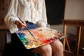 Female painter holds color palette and brush