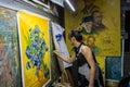 A female painter painting a Vincent van Gogh`s famous masterpice in her studio in Dafen Oil painting village of Shenzhen, China