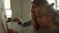 Female painter teaching children in studio. Boy and girl painting indoors.