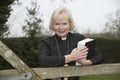 Female parish priest on a house call entering the garden gate