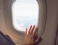 A female passenger of the flight sitting near the window, holding a hand out the window in anticipation of landing