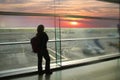 Female passenger, waiting for his flight, stands at the window and looks at the airport runway, a travel concert
