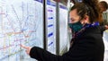 Female passenger wearing face covering mask during covid-19 lockdown using london underground metro train map in england