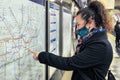 Female passenger wearing face covering mask during covid-19 lockdown using london underground metro train map in england