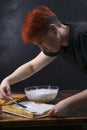 A female pastry chef decorates cake shortcakes with white cream from a glass bowl with a spatula Royalty Free Stock Photo