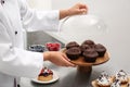 Female pastry chef with tasty cupcakes at table in kitchen Royalty Free Stock Photo