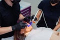 Female patient in bib and orange UV protective glasses in a dental clinic. Dentist in gloves using UV lamp.