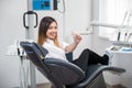 Female patient with perfect white teeth sitting in dental chair after treatment at modern dental clinic Royalty Free Stock Photo