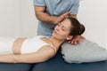 Female patient receiving osteopathic neck and shoulder treatment. Therapist manipulating back of head and chest. A girl