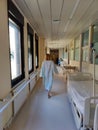 Female patient wearing hospital robe walking in long empty hospital hallway. Royalty Free Stock Photo