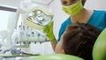 Female pediatric dentist looking at child patient teeth, adjusting light, cure Royalty Free Stock Photo