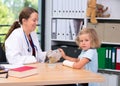 Female pediatrician bandaging the arm of a little girl