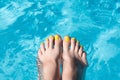 Female with perfect yellow pedicure over a pool. Vacation pericure. Female bare feet in a blue swimming pool water Royalty Free Stock Photo