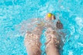 Female with perfect yellow pedicure over a pool. Vacation pericure. Female bare feet in a blue swimming pool water Royalty Free Stock Photo