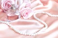 Female perfume bottle, rose, pearls on pink silk