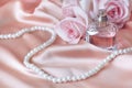 Female perfume bottle, rose, pearls on pink silk