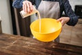 Female person adds cream into a bowl, cake cooking