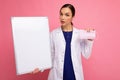 Female person doctor in a white medical coat holding blank board with copy space for text and protective mask isolated Royalty Free Stock Photo