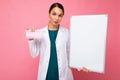 Female person doctor in a white medical coat holding blank board with copy space for text and protective mask isolated Royalty Free Stock Photo