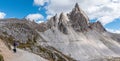 A female person hiking lonely with her dog around the Drei Zinnen mountains, the Dolomites in South Tirol