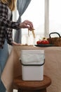 Female person recycling food leftovers in a compost bin. Woman cooking at home and throwing compostable organic waste in a bokashi